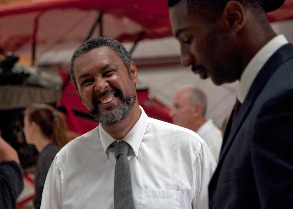 A man smiles as he talks to another man on a film set.