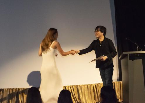 A woman shakes a man's hand on a stage.