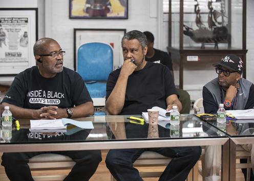 Three men sit at a table in discussion.